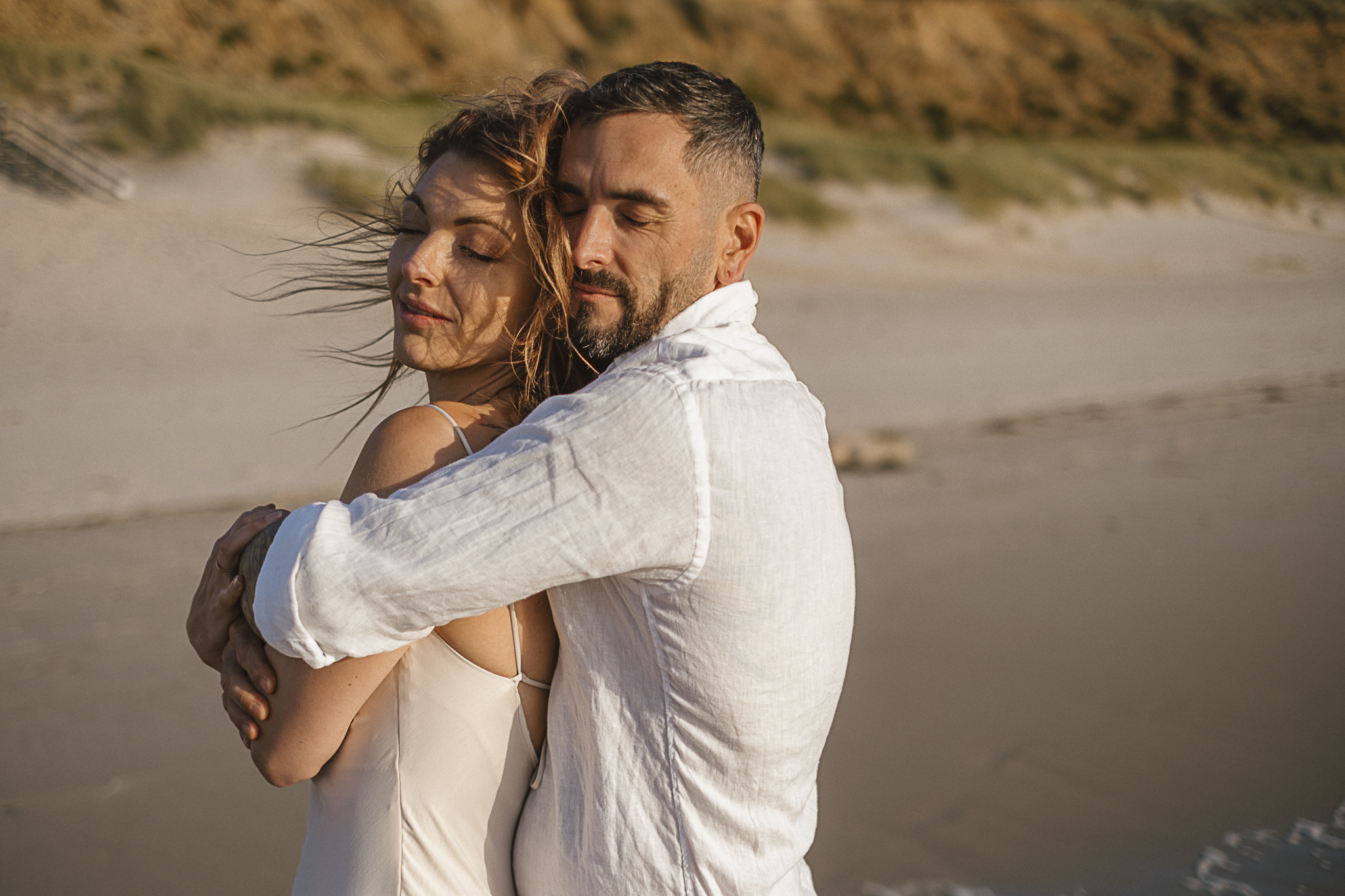Romantisches After-Wedding-Shooting auf Sylt bei Sonnenuntergang – ein verliebtes Brautpaar genießt den Moment am Strand, barfuß im Sand, mit Blick aufs Meer. Sanftes Licht, echte Emotionen und eine natürliche Kulisse machen dieses Paarshooting zu einem unvergesslichen Erlebnis.